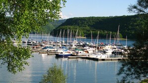 A marina with various boats docked, surrounded by greenery and hills. - VVF Jura Lac de Vouglans, Maisod (Maisod)
