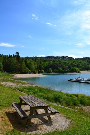 A picnic table by a lake with boats in the background. - VVF Jura Lac de Vouglans, Maisod (Maisod)