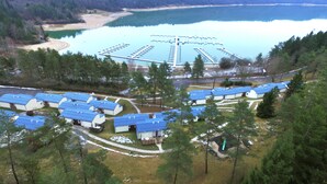 A lakeside resort with multiple blue-roofed cabins arranged in a semi-circle around a central dock. - VVF Jura Lac de Vouglans, Maisod (Maisod)
