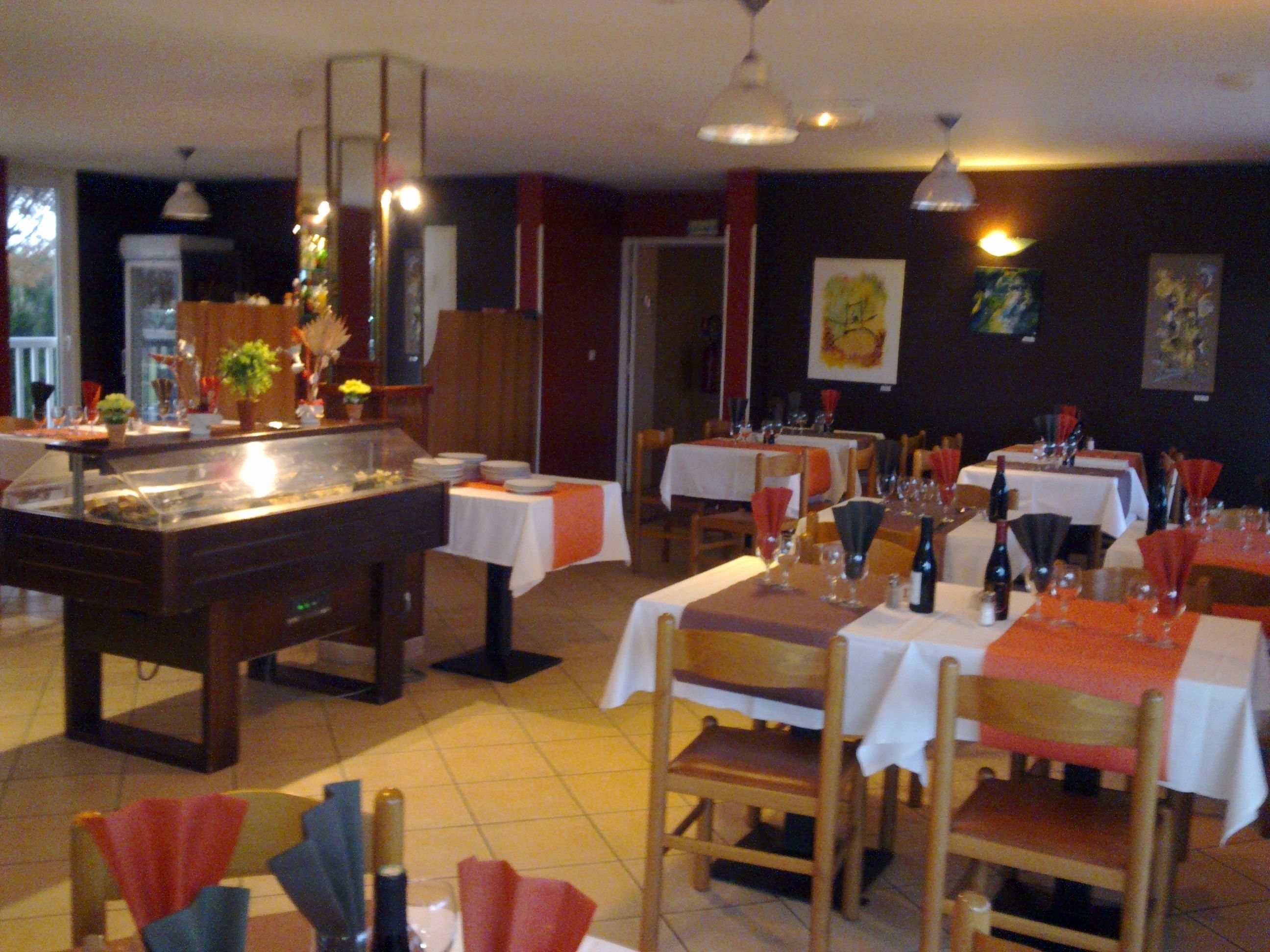 A restaurant with multiple tables set for dining, a buffet area, and artwork on the walls.