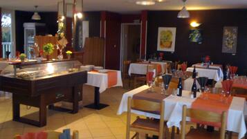 Een restaurant met meerdere tafels gedekt voor diners, een buffetgedeelte en kunstwerken aan de muur.