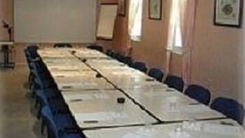 Ein Konferenzraum mit langem Tisch, Stühlen, einer Projektionsleinwand und einer Whiteboard-Tafel.