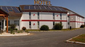 A hotel with a central entrance, solar panels on the roof, and a red and white facade.
