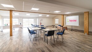 A conference room with a whiteboard, a projector screen displaying 'fasthotel', and a table with chairs.