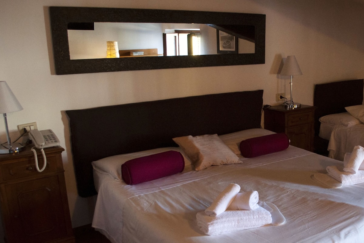 Une chambre d’hôtel avec deux lits, une table de chevet avec une lampe, un téléphone et un tableau encadré au mur.