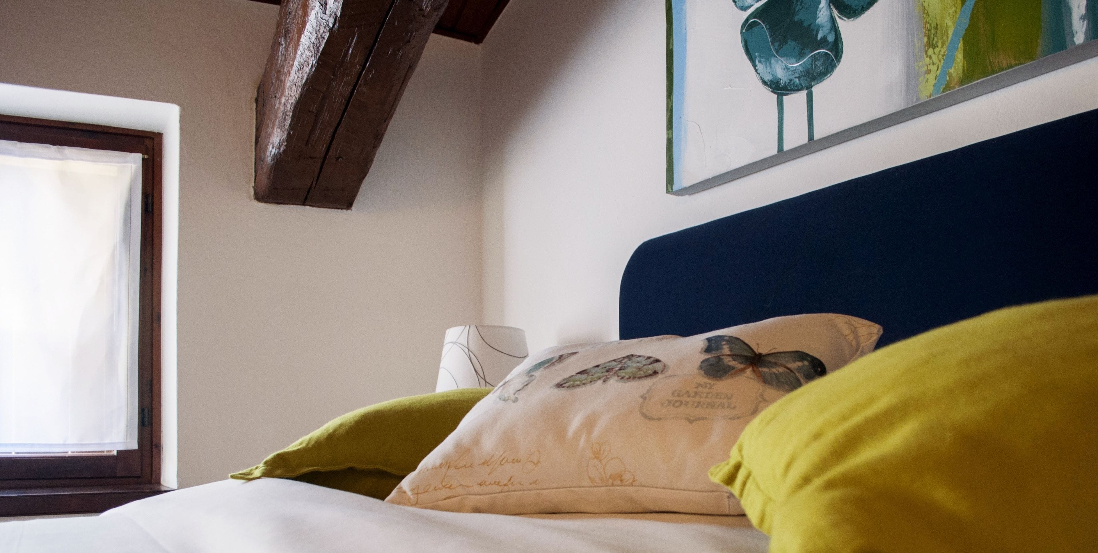 Une chambre à coucher avec un lit, des oreillers, une fenêtre et un tableau au mur.