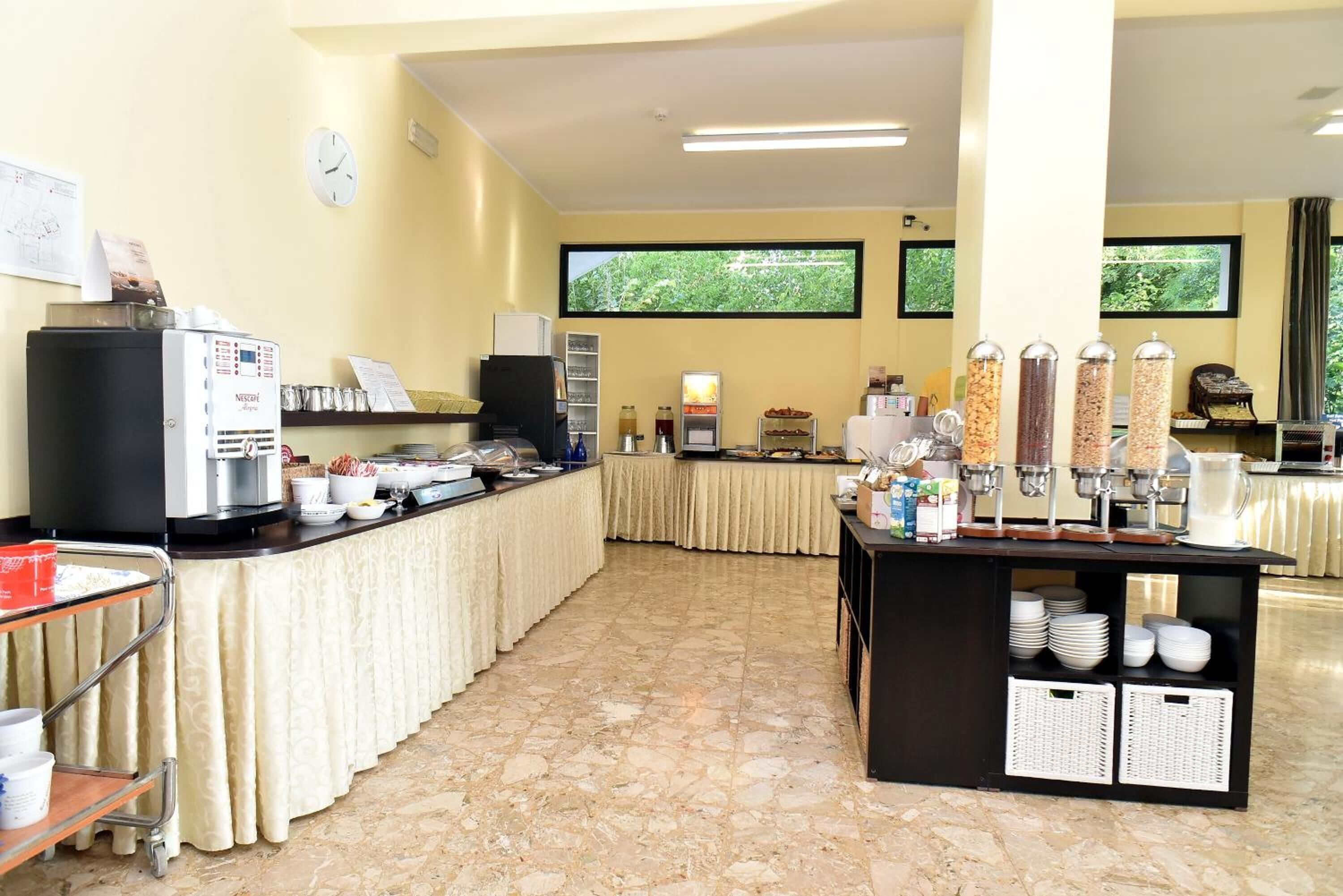 Ein geräumiger Raum mit einem Buffet, inklusive Kaffeemaschine, Kühlschrank und verschiedenen Speisenspendern.