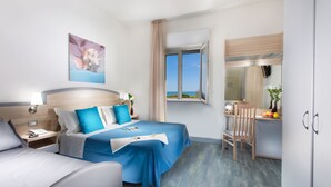A hotel room with a bed, a desk, a chair, and a window with a view. - Hotel Beau Soleil (Cesenatico)