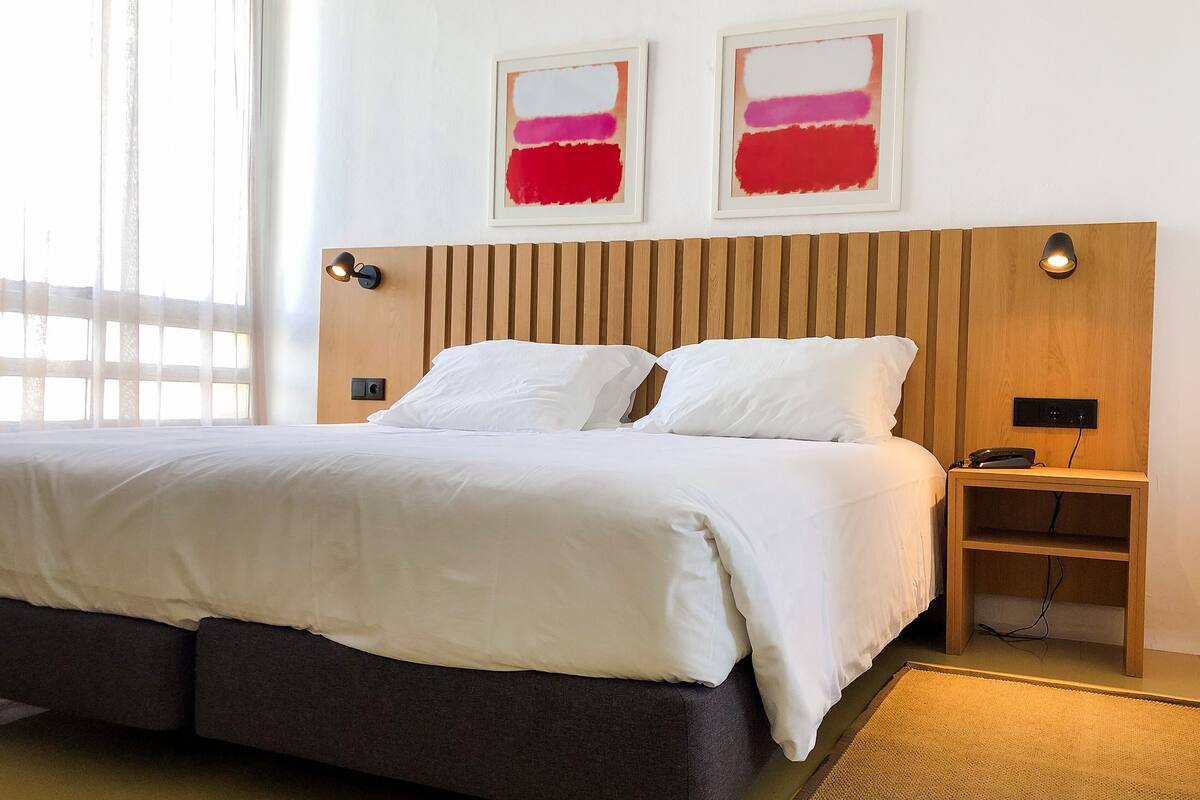 Une chambre d’hôtel avec un lit, des tables de chevet et des œuvres d’art accrochées au mur.