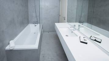 Ein modernes Badezimmer mit einer großen Badewanne, einem langen Waschtisch mit Spiegel und einer Duschkabine.