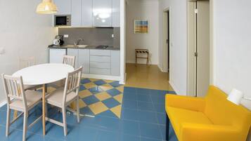 A compact living space with a kitchen, dining area, and a yellow armchair.