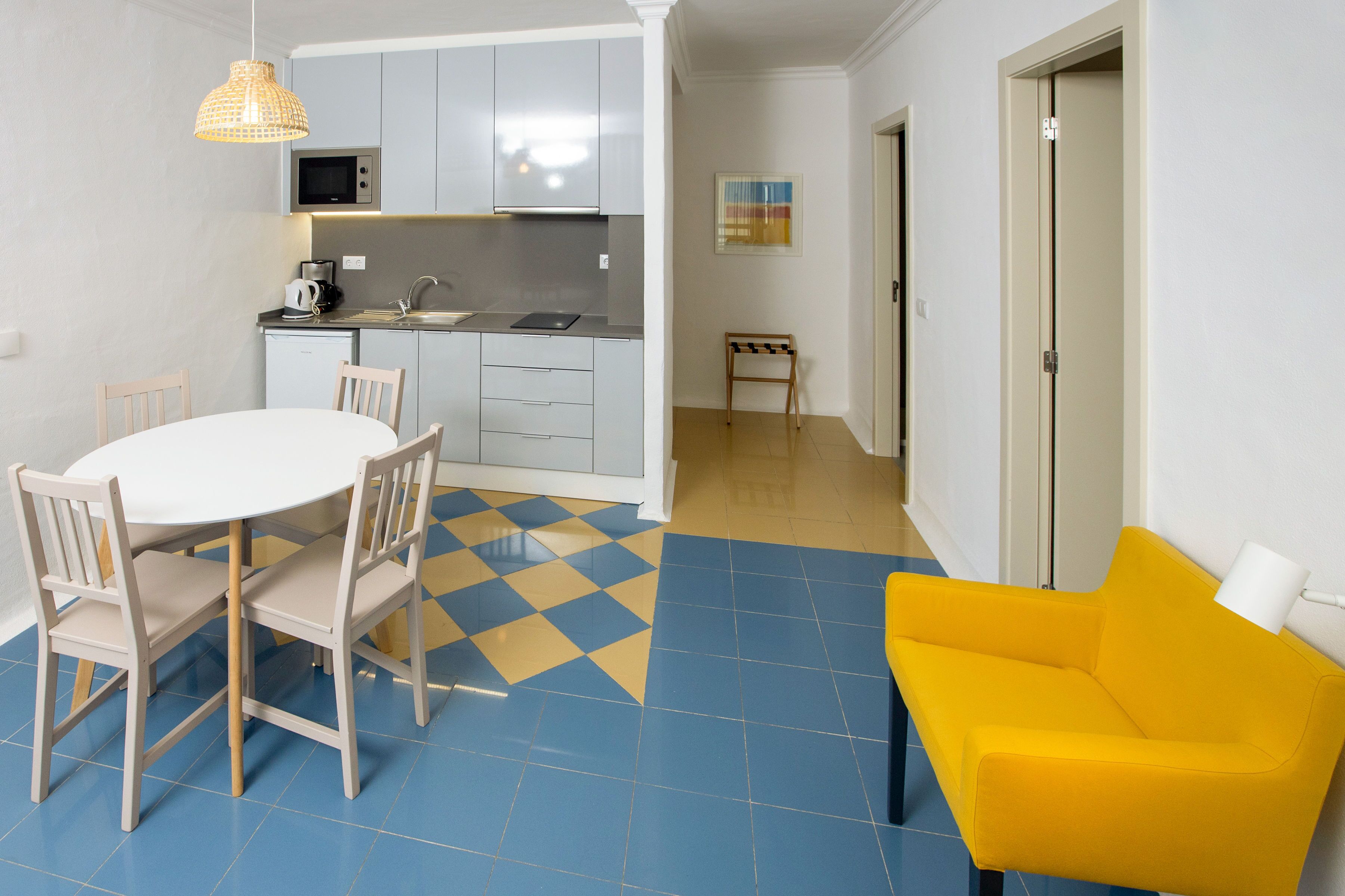 Un espacio habitable compacto con cocina, comedor y un sillón amarillo.