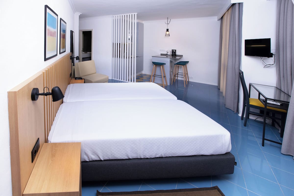 Une chambre d’hôtel avec un grand lit, un bureau avec deux chaises, une télévision et une petite table.