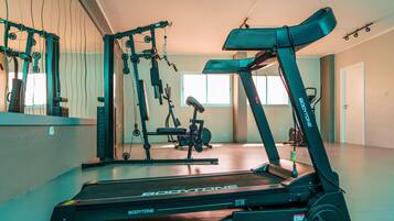 A gym with a treadmill, weight machines, and a bench.