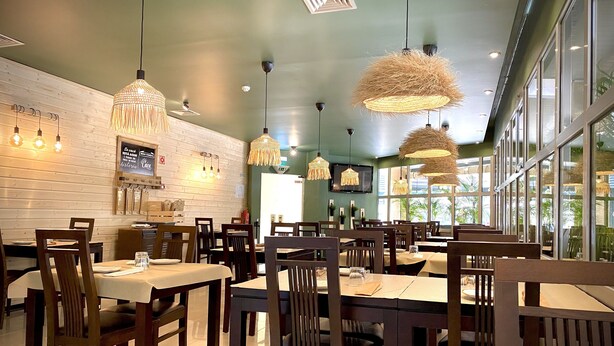 A restaurant interior with wooden tables and chairs, hanging pendant lights, and large windows allowing natural light. - Hotel Apartamentos Foz Atlântida (Vila Real Santo Antonio)