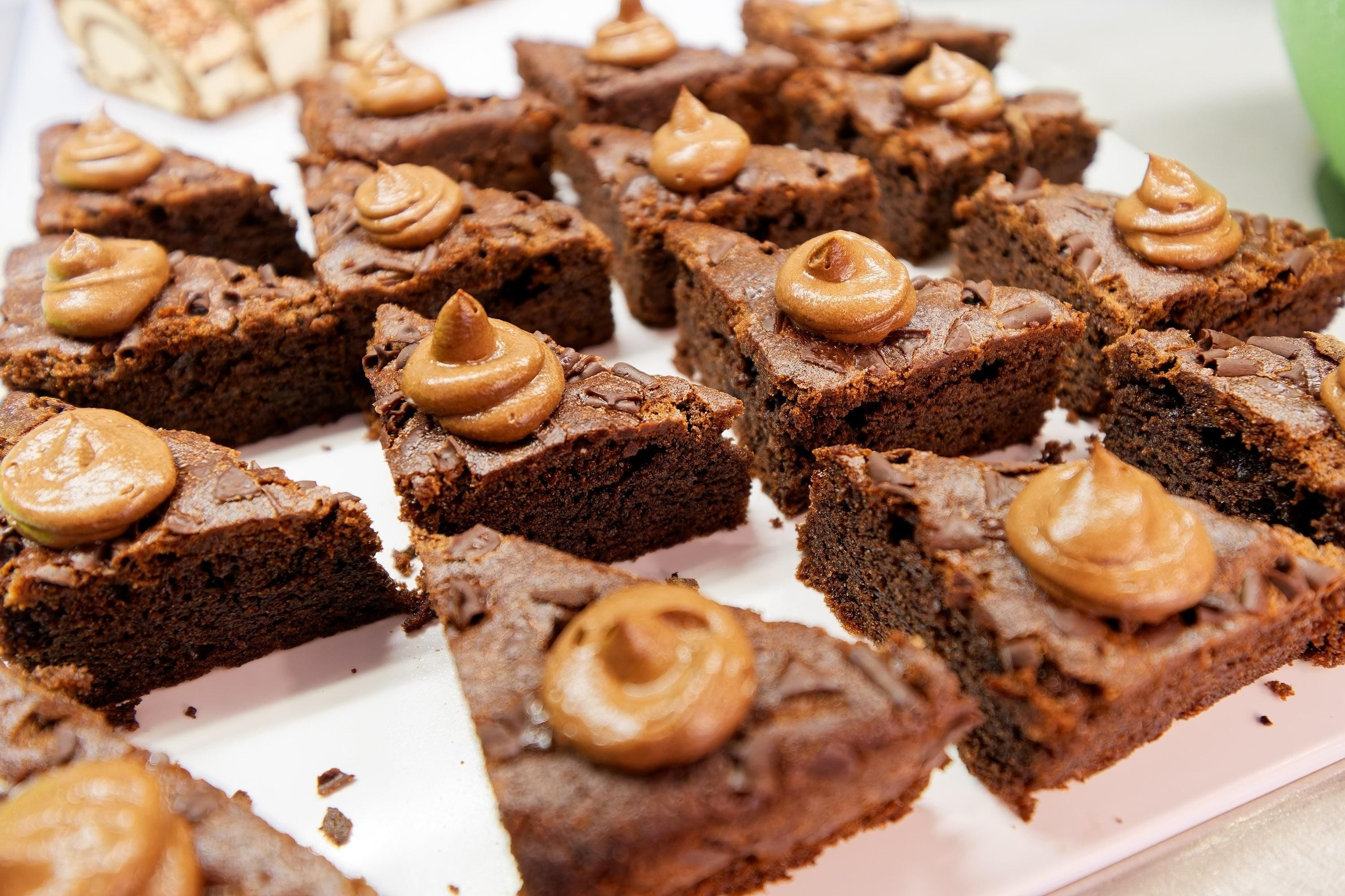 A tray of brownies with a dollop of a brown spread on top.