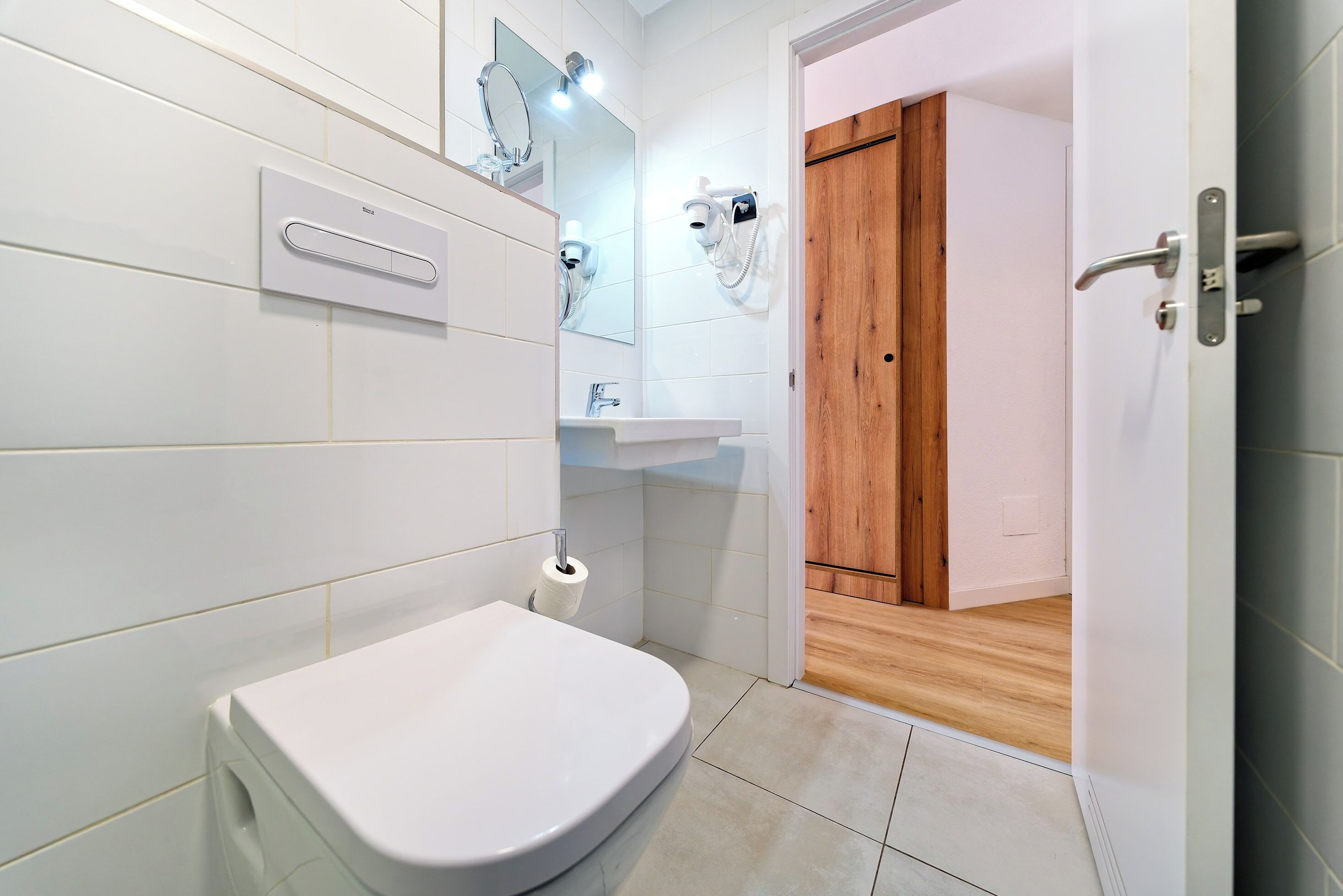 Une salle de bain moderne équipée de toilettes, d’un lavabo et d’un sèche-cheveux, le tout fixé au mur.