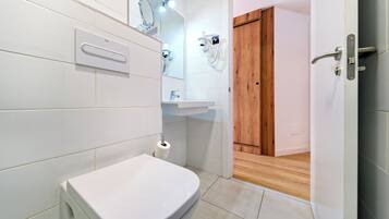 Une salle de bain moderne équipée de toilettes, d’un lavabo et d’un sèche-cheveux, le tout fixé au mur.