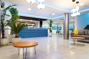 A modern lobby with a bar area, seating, and potted plants. - Servatur Alameda de Jandía (Pajara)