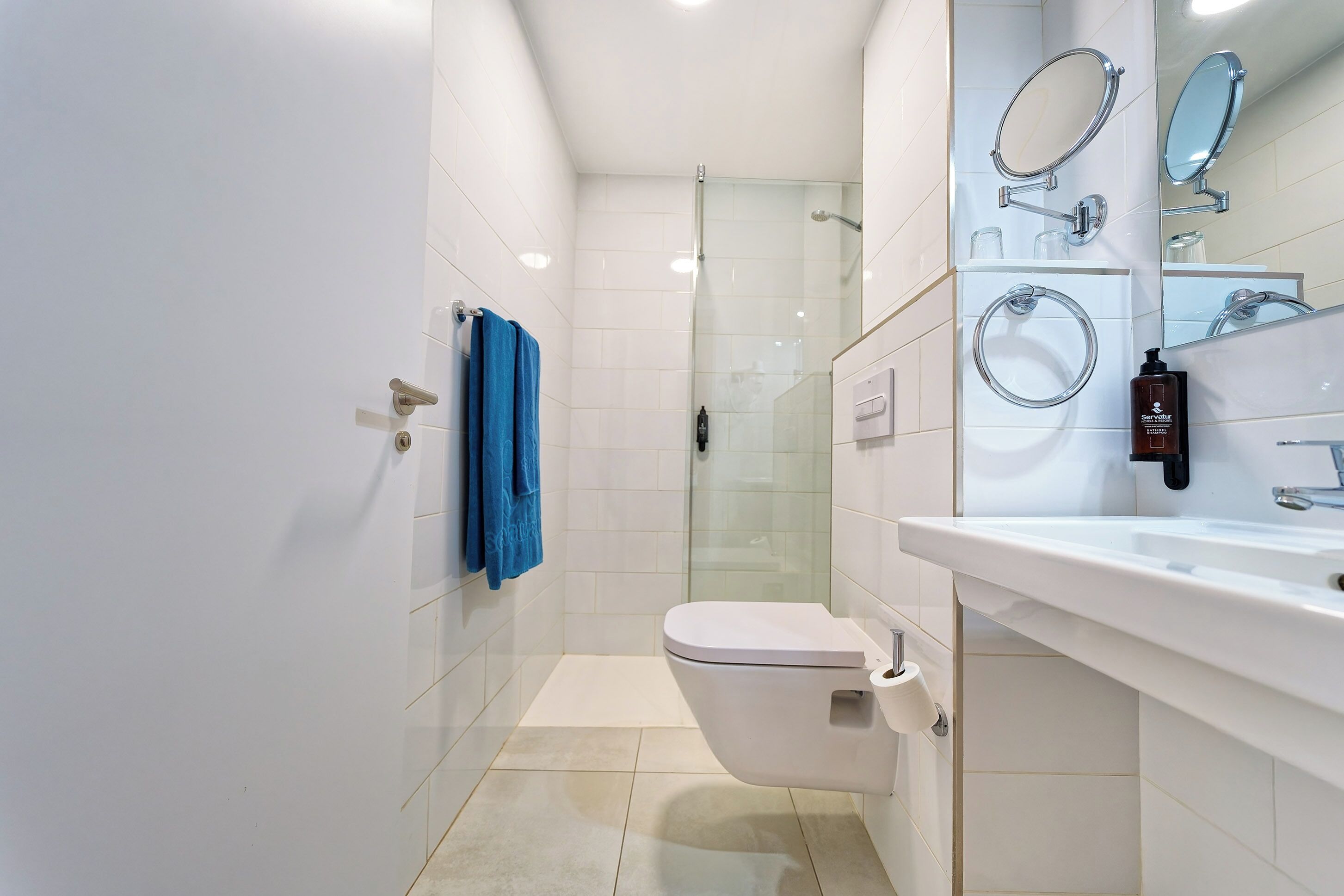 Une salle de bain moderne avec une douche à parois de verre, des toilettes blanches et un lavabo avec un miroir au-dessus.