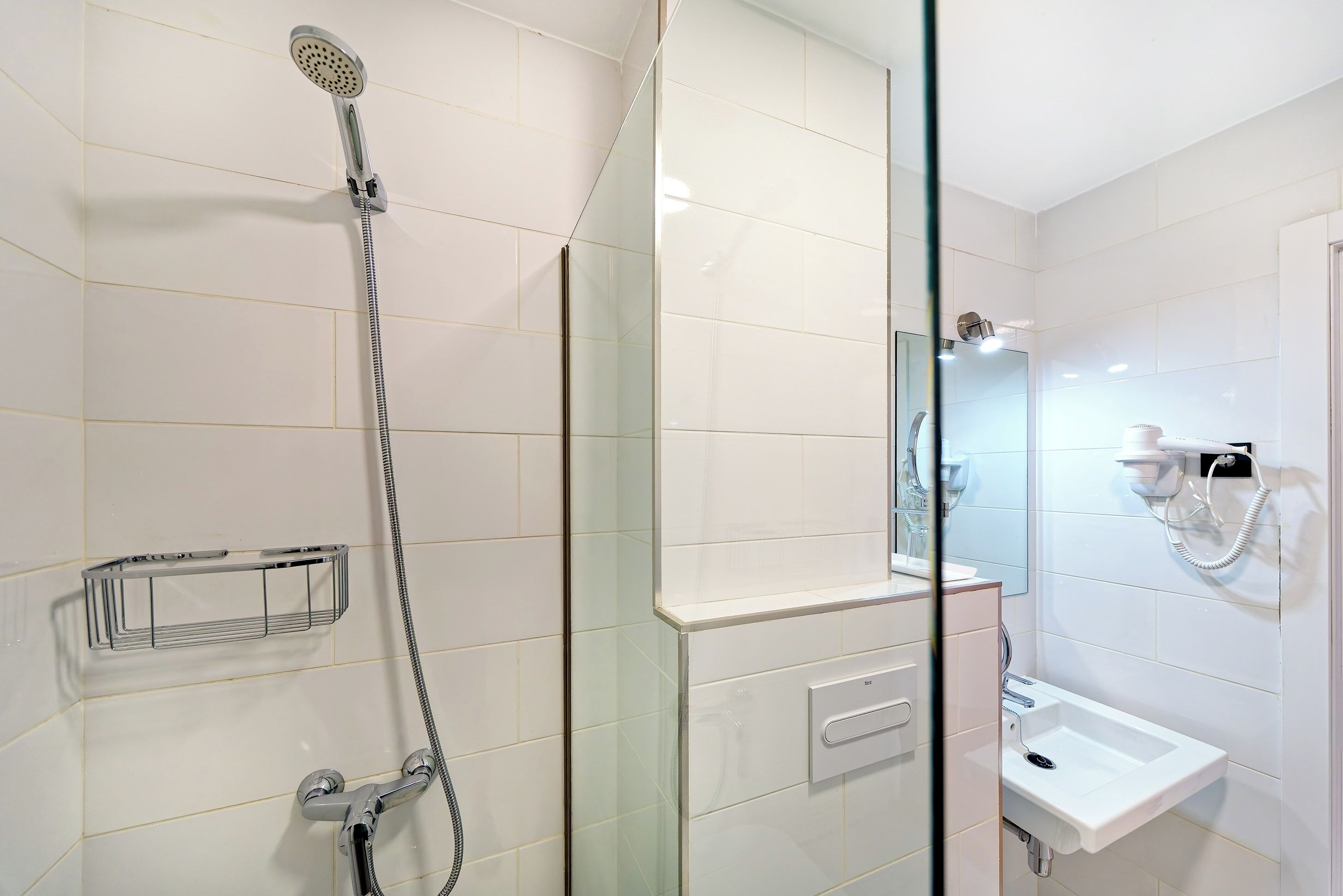 Une salle de bain moderne avec une douche en verre, un lavabo blanc et un miroir au-dessus du lavabo.