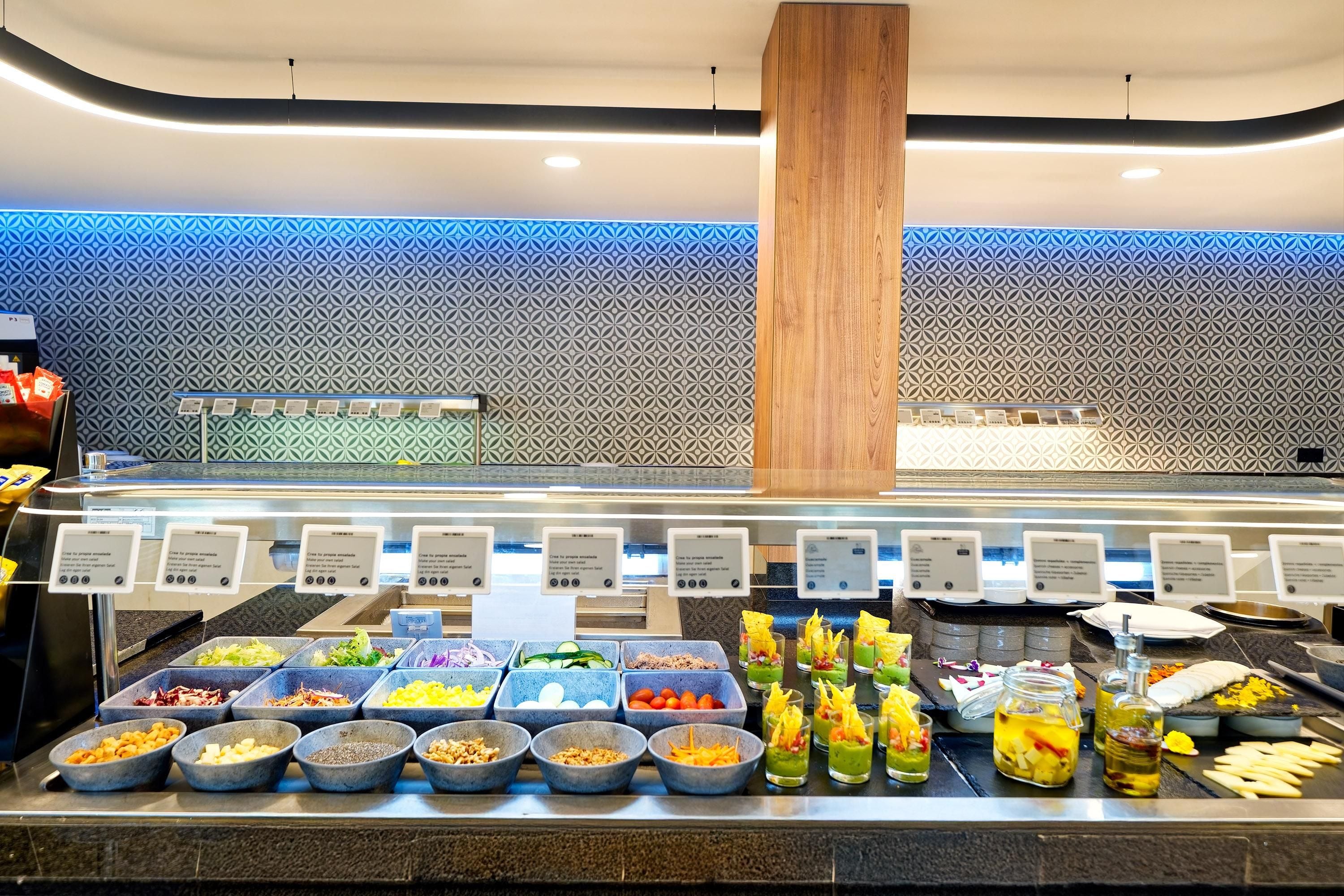 A buffet with various food options and a wooden column in the center.
