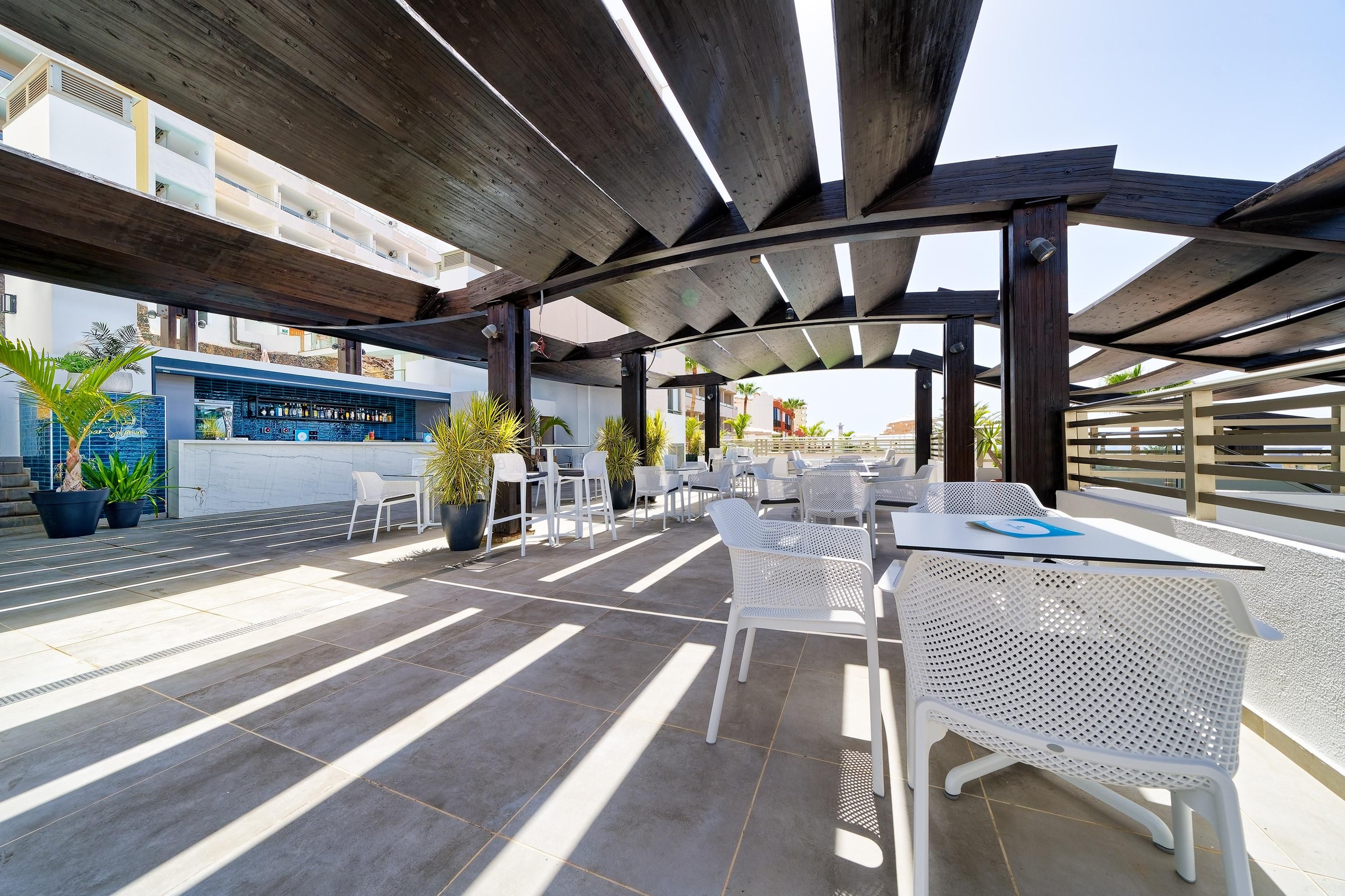 Eine Außenpatio-Terrasse mit Tischen, Stühlen, einer Bar und Kübelpflanzen.
