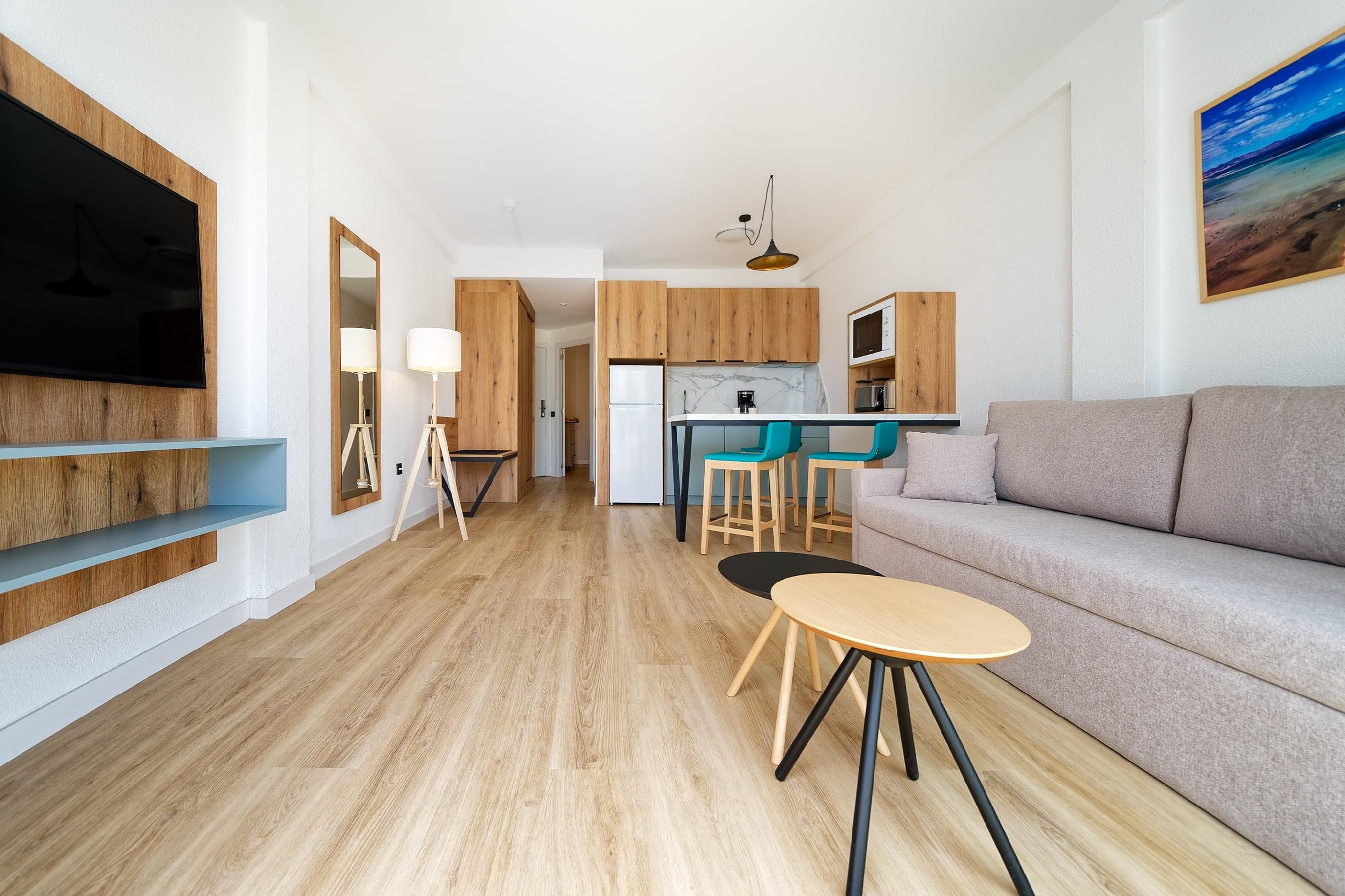 A modern living room with a sofa, a coffee table, and a TV mounted on the wall.
