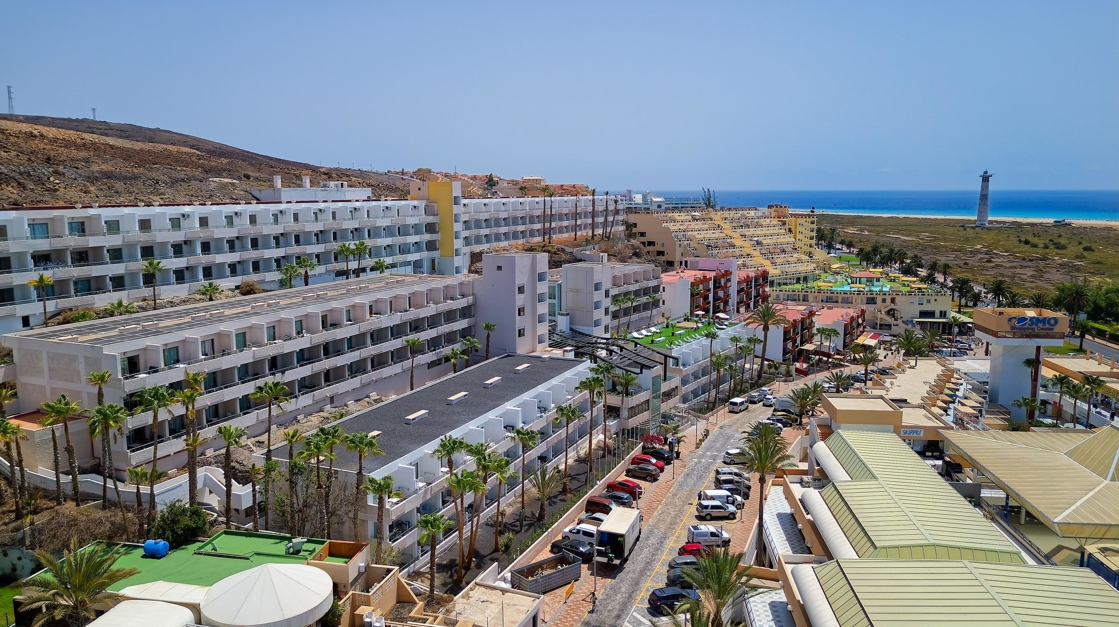 Un hôtel situé sur la côte, composé de plusieurs bâtiments à étages, doté d’un parking et offrant une vue sur la mer.