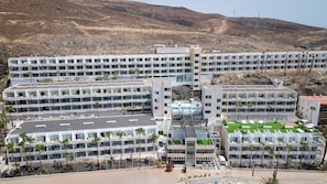 Un hotel de varios pisos con un patio central, mobiliario exterior y una zona de piscina.