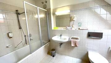A bathroom with a glass-enclosed shower, a sink, a toilet, and a mirror.