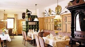 Un comedor con mesas y sillas de madera, un gramófono antiguo y una pared con diseño verde.