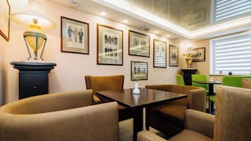 Un coin repas avec une table et des chaises, des tableaux encadrés au mur et une lampe.