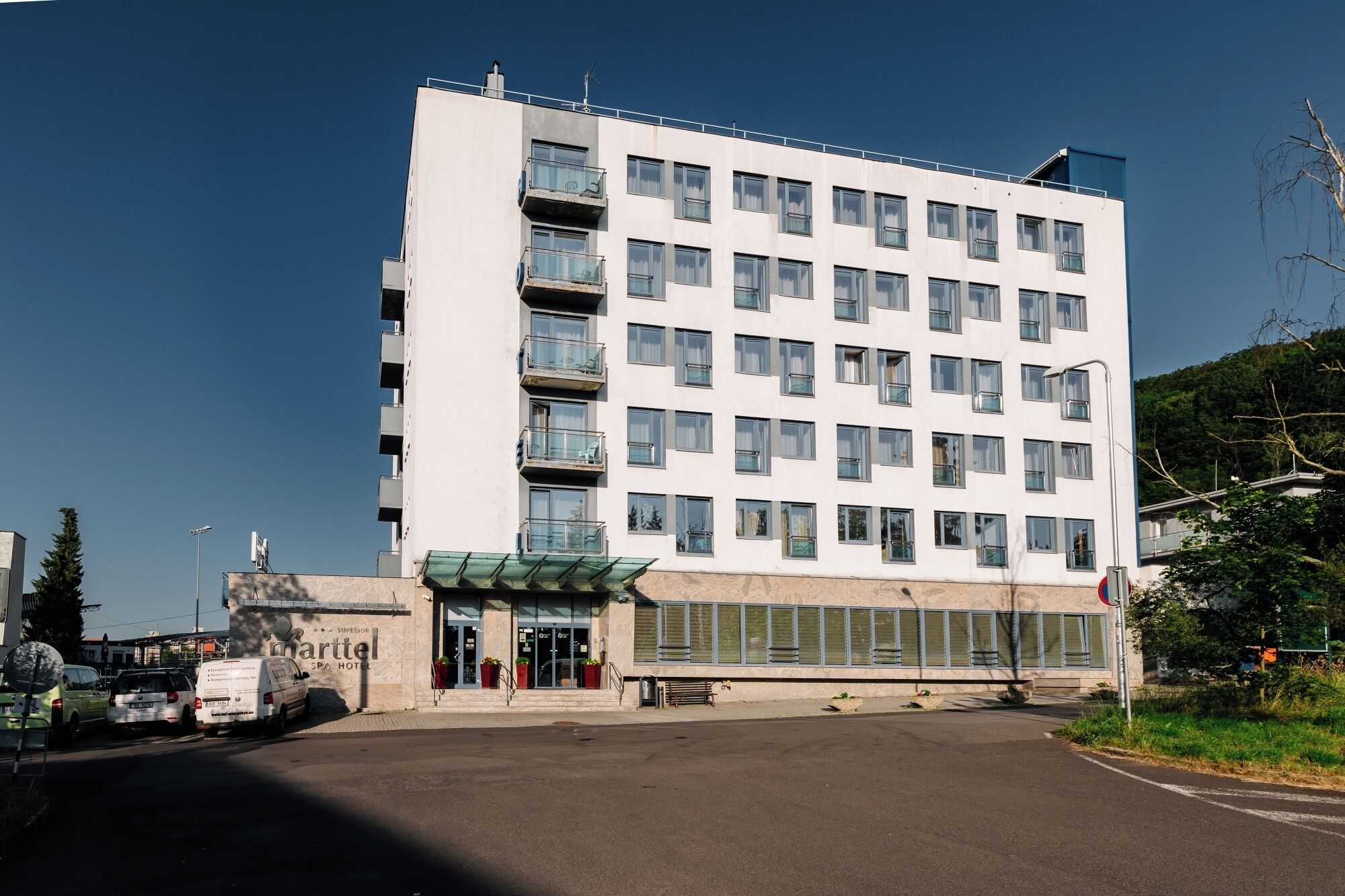 A multi-story hotel with a flat facade, large windows, and a green awning over the entrance.