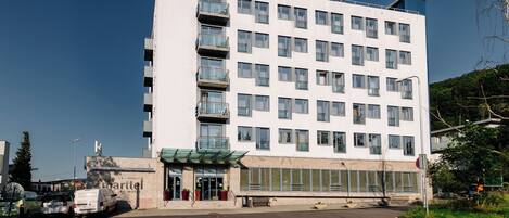 A multi-story hotel with a flat facade, large windows, and a green awning over the entrance.