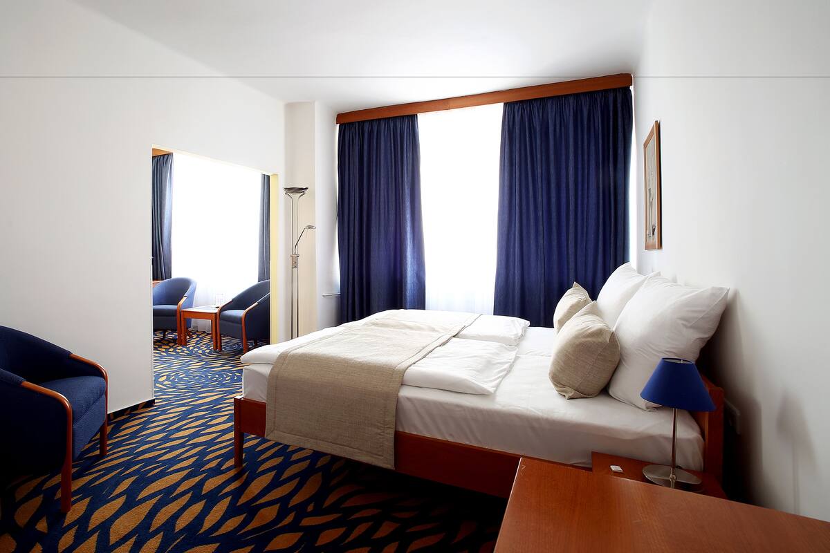 Ein Hotelzimmer mit Bett, Schreibtisch, Stuhl und Lampe.