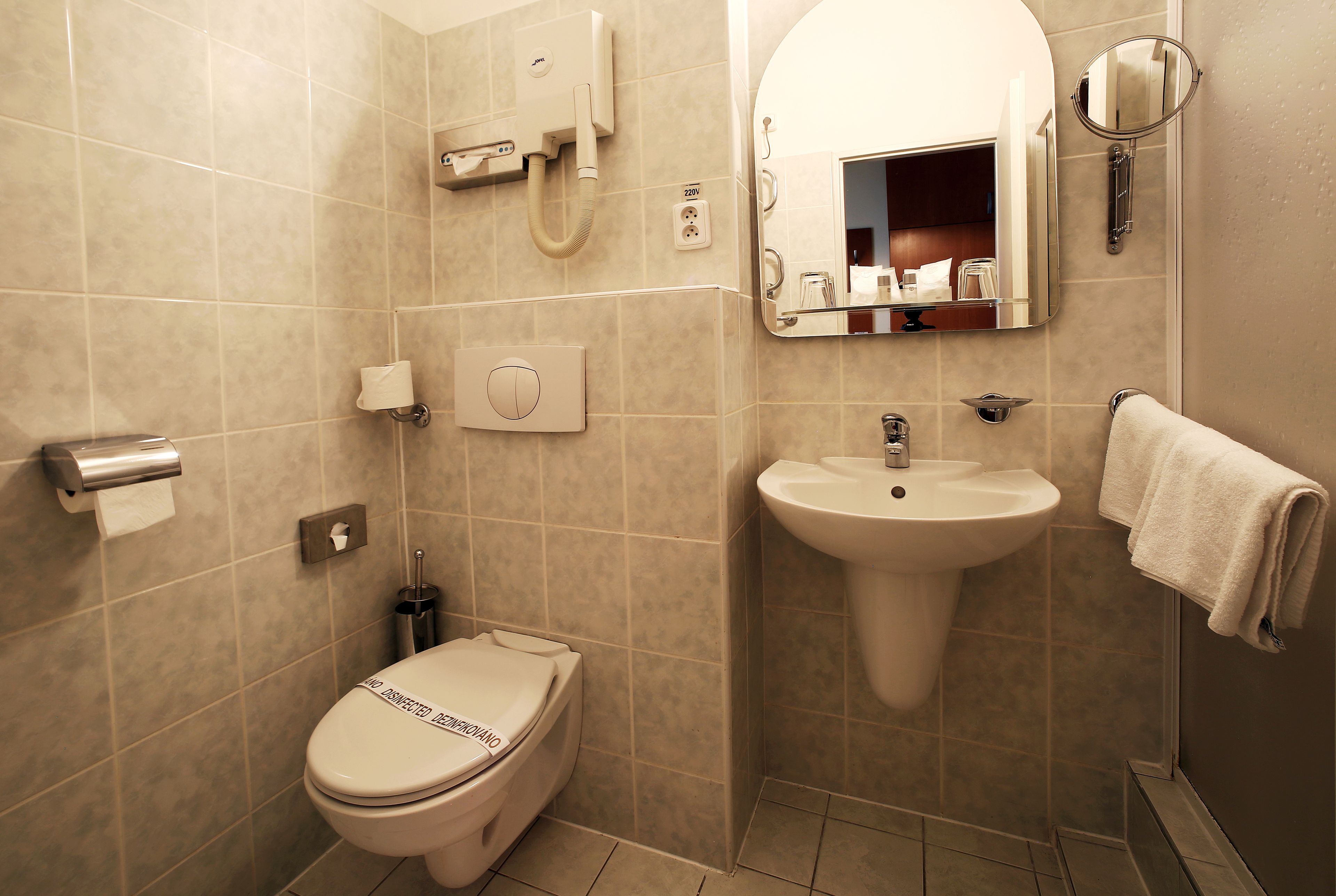 Een moderne badkamer met toilet, wastafel, spiegel en handdoekrek.