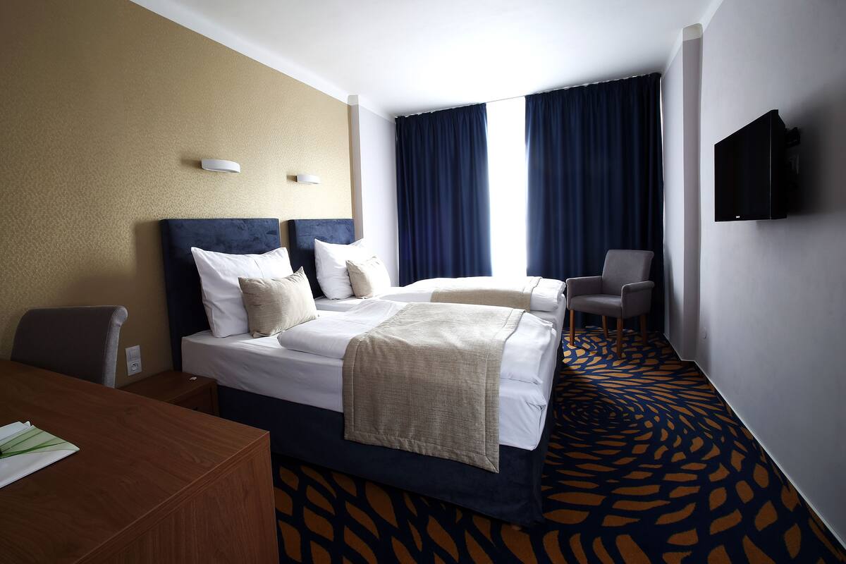 Ein Hotelzimmer mit Bett, Schreibtisch, Stuhl und Fernseher.