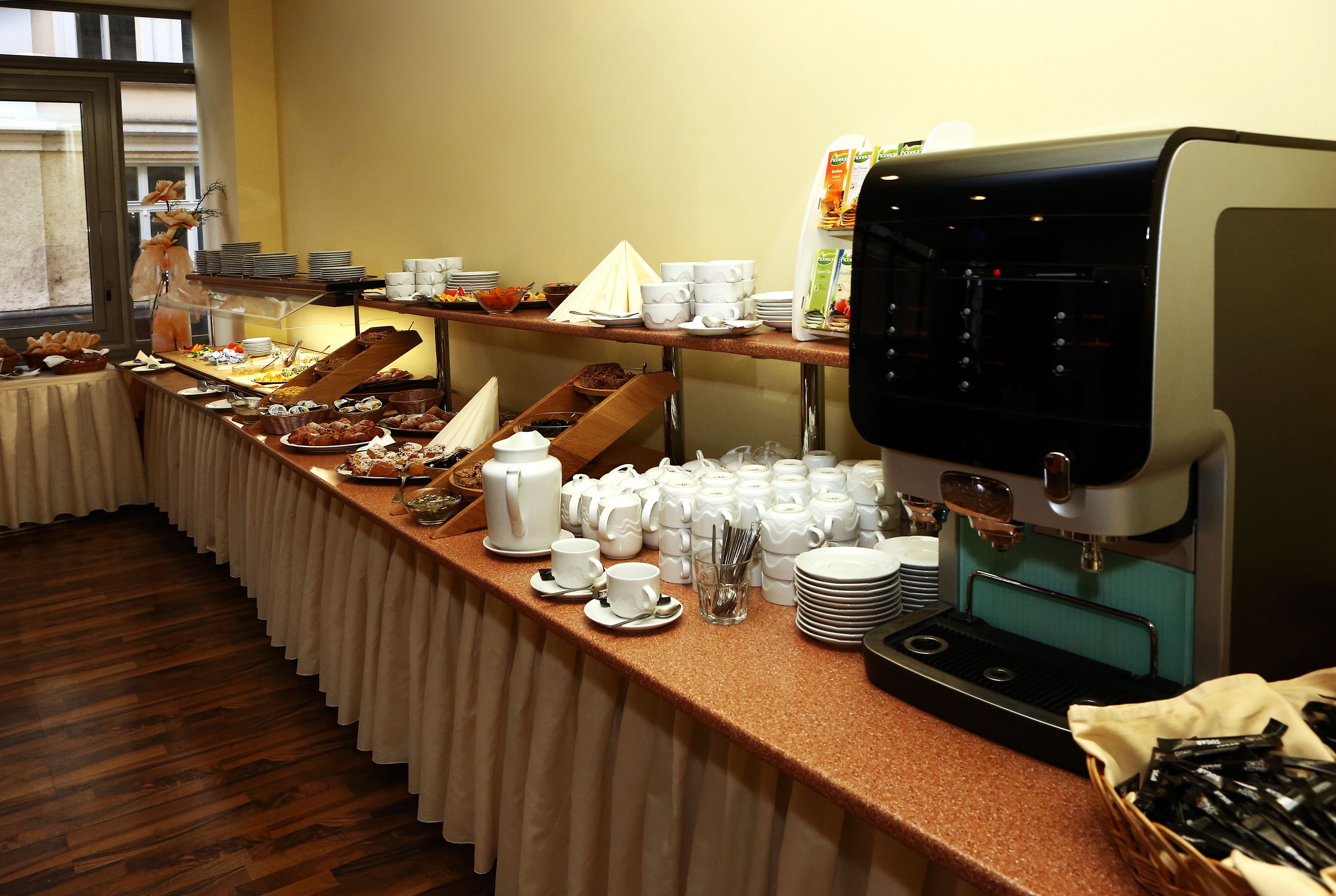 A buffet setup with various food items, coffee machines, and dining ware.