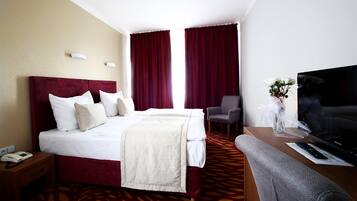 Una camera d'hotel con un letto grande, una televisione, una scrivania e una sedia.