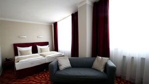 A hotel room with a bed, a sofa, and a patterned carpet. - Central Hotel Pilsen (Plzen)