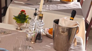 A table set for dining with a view of the sea, a bottle of champagne, and a bowl of fruit. - Hotel Rivamare (Jesolo)