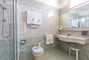 A bathroom with a glass shower enclosure, a toilet, a sink, and a mirror. - Hotel Rivamare (Jesolo)