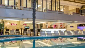 A hotel lobby with a pool, seating area, bar, and a staircase. - Hotel Rivamare (Jesolo)