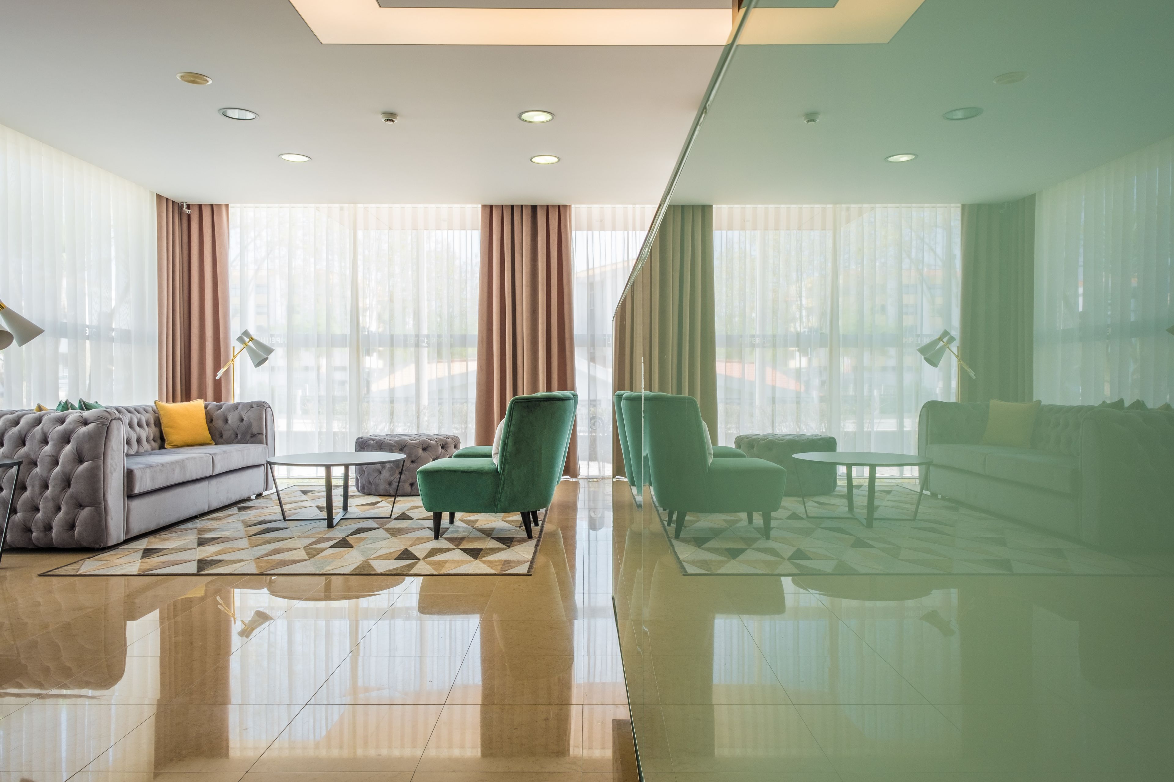 Un moderno vestíbulo de hotel con un sofá, sillones, una mesa de centro y un separador de vidrio.