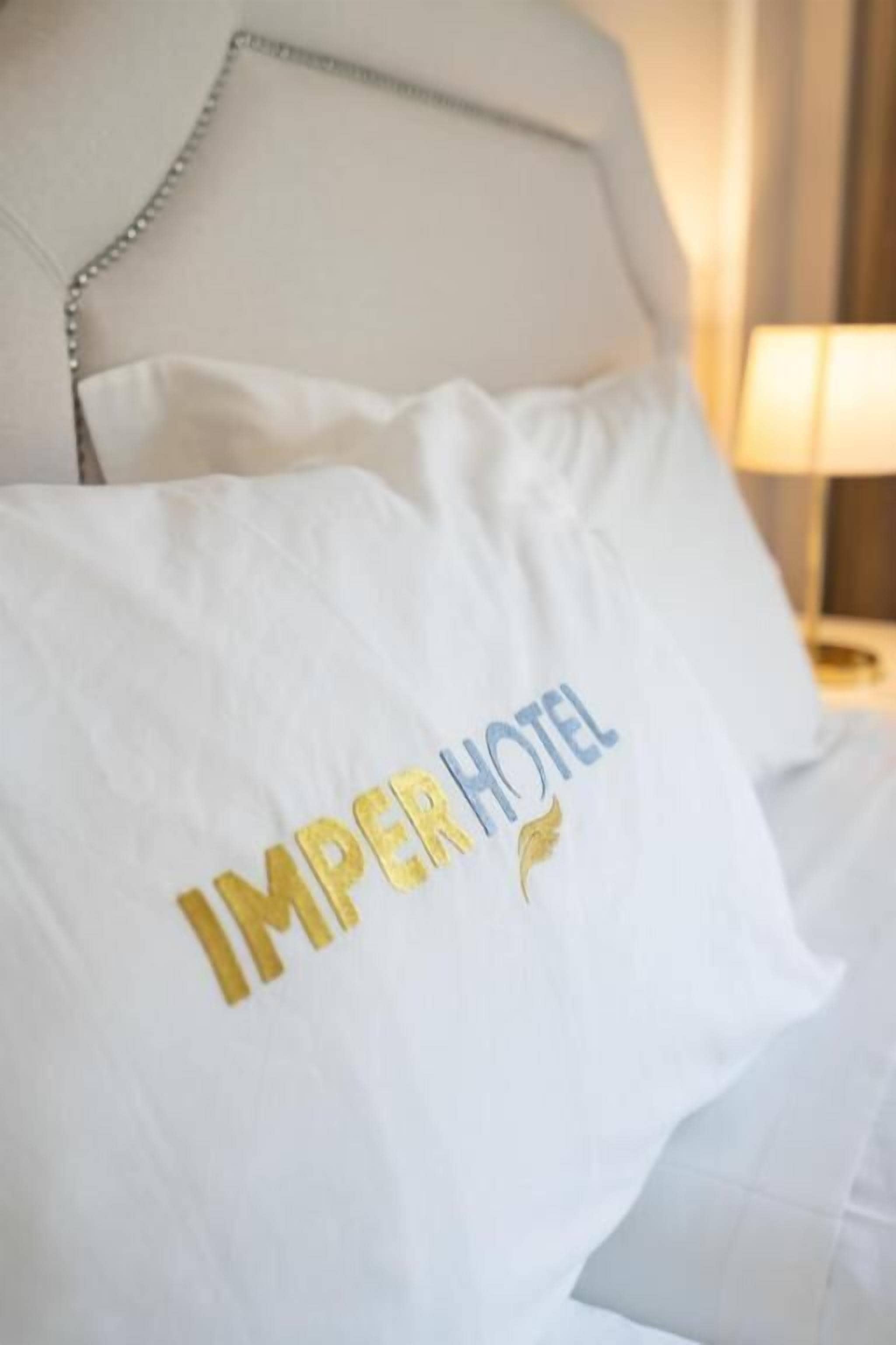 A white pillow with "IMPER HOTEL" embroidered in gold lettering.