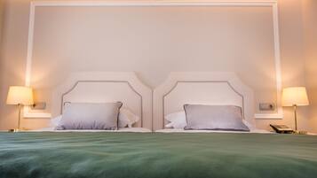 Una cama doble con una colcha verde, dos lámparas de noche y un teléfono en la mesita de noche.