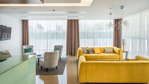 A modern living room with a yellow sofa, a glass coffee table, and a TV mounted on the wall. - Imperhotel by Umbral (Ourem)