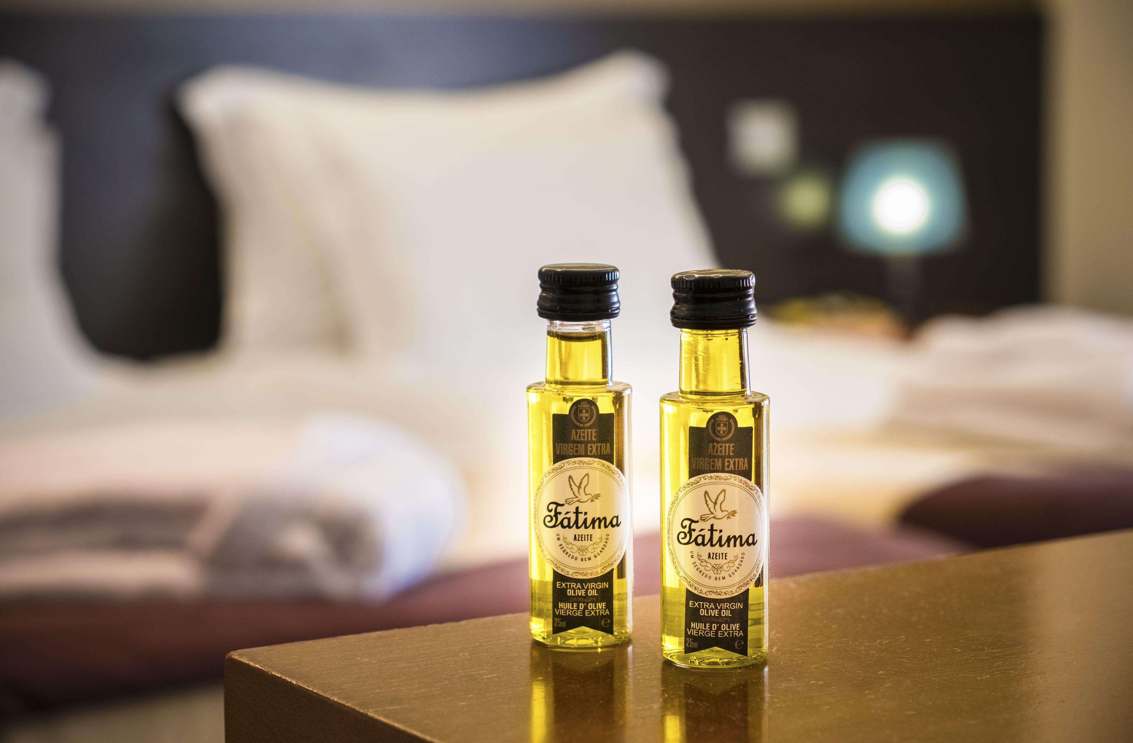 Twee flessen Fatima extra vergine olijfolie op een tafel in een hotelkamer.