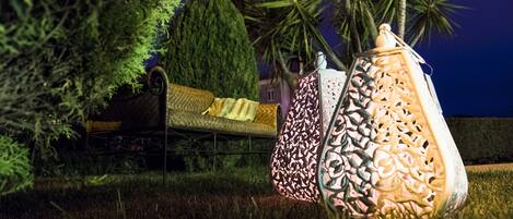 Un espacio al aire libre con asientos nocturnos, un sofá y faroles con diseños.